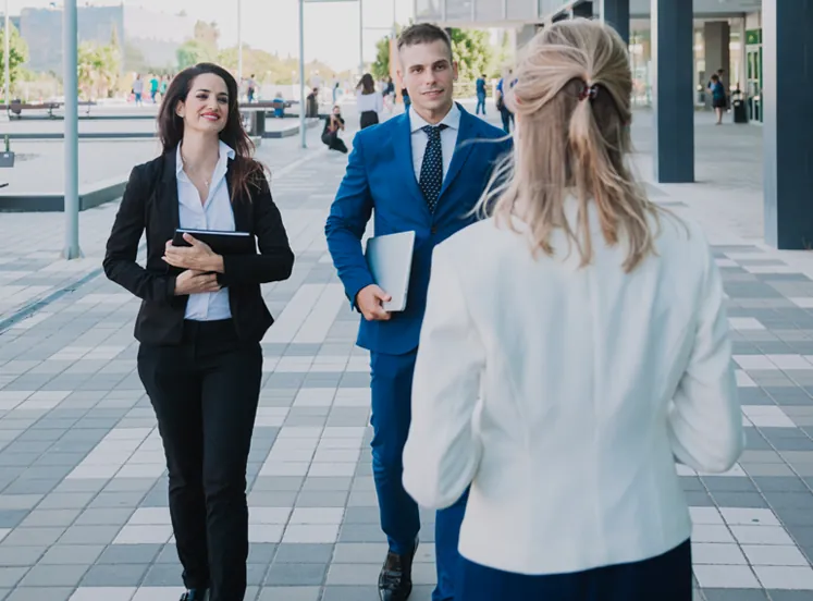 Project team discussing plans outside a modern glass office building